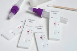 A collection of test strips alongside a bottle of liquid for Rapid Influenza and Covid testing.