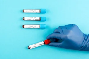 A doctor in blue gloves holds a blood tube, indicating a Rapid Influenza and COVID test procedure.