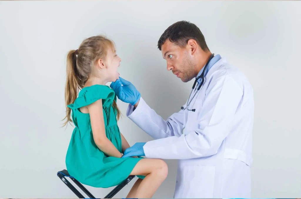 A pediatric doctor swabbing a young girl's throat for a strep test in a well-lit, child-friendly clinic