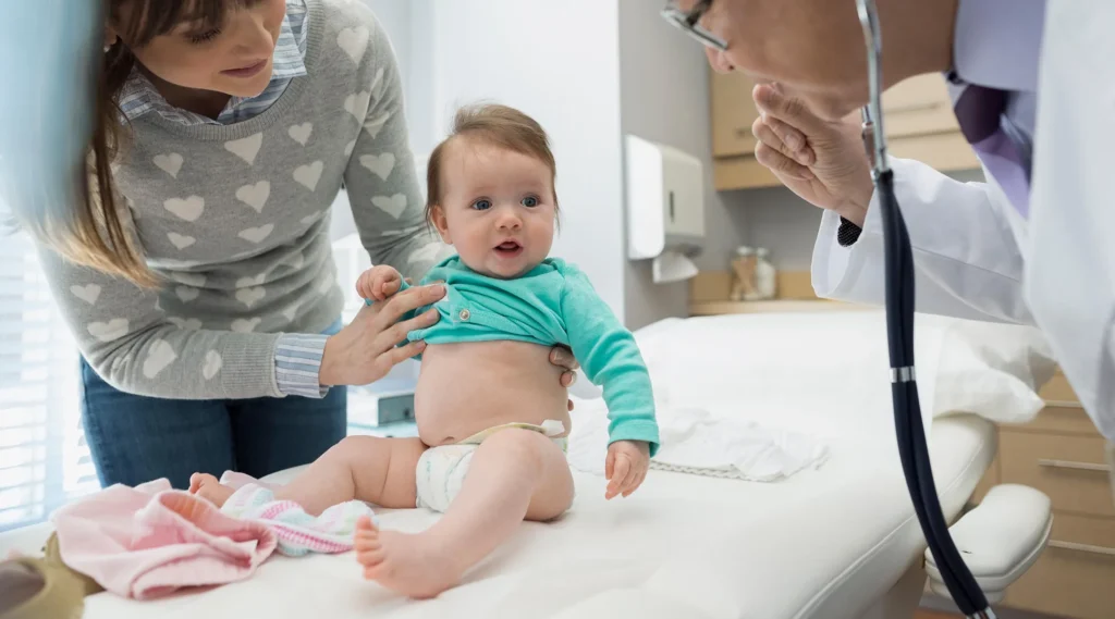 a baby sitting on a bed being Annual-Medical-Check-Up by a doctor