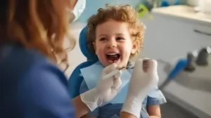 A smiling child receiving a dental checkup from a dentist. The child is sitting in a dental chair, and the dentist is holding dental instruments, examining the child's teeth in a clinical setting.