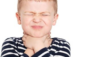 A young boy with his hands on his neck, showing signs of pain associated with strep throat